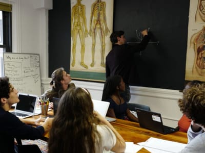Dan Lerman teaching a small SAT class at a whiteboard