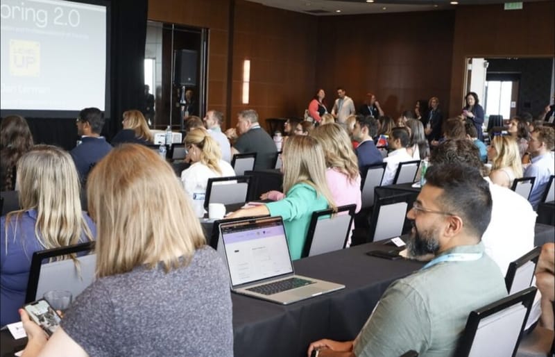 Attendees seated at a tutoring industry conference watch Dan Lerman's 'Tutoring 2.0' presentation on screen.