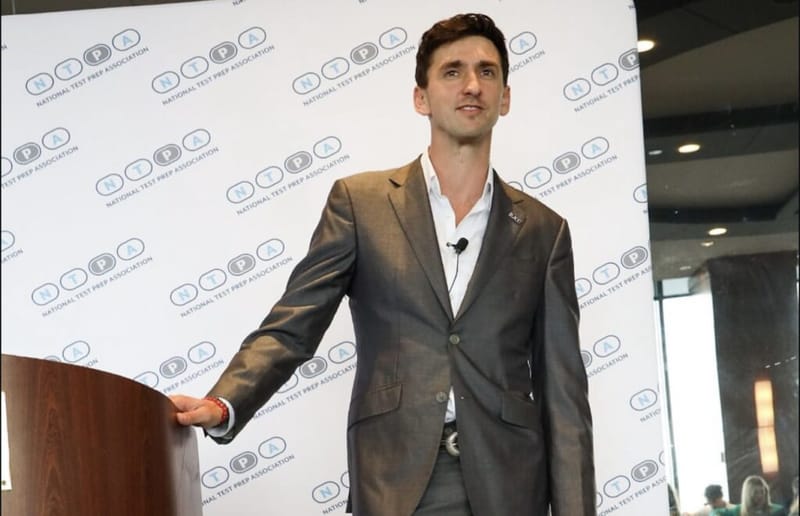 Dan Lerman stands at a podium in front of a National Test Prep Association backdrop.