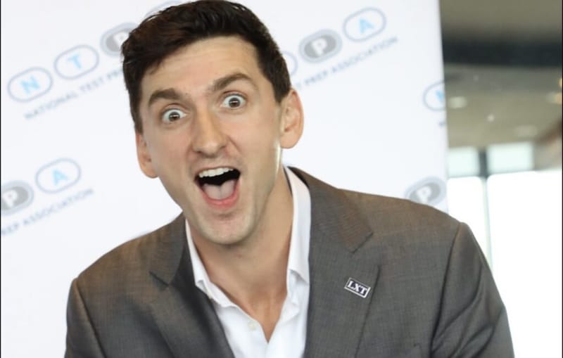 Dan Lerman makes an excited expression in front of a National Test Prep Association backdrop.