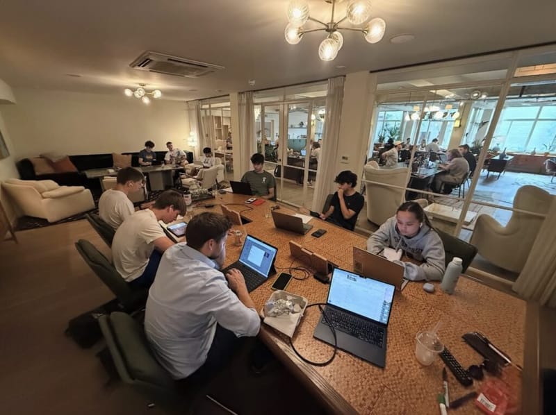 Students study on laptops around a long table during the London SAT boot camp.